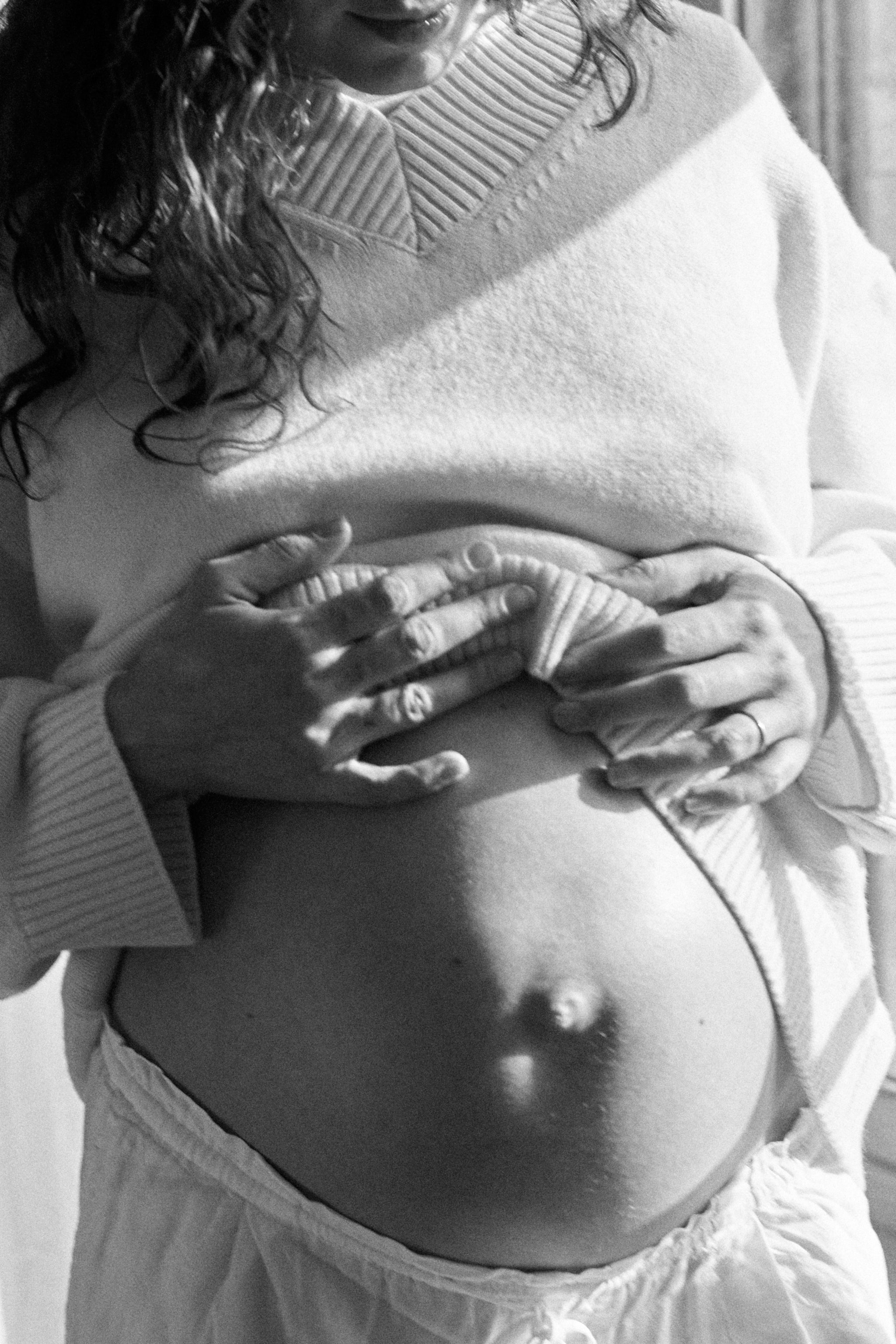 Pregnant woman lifting sweater to show belly