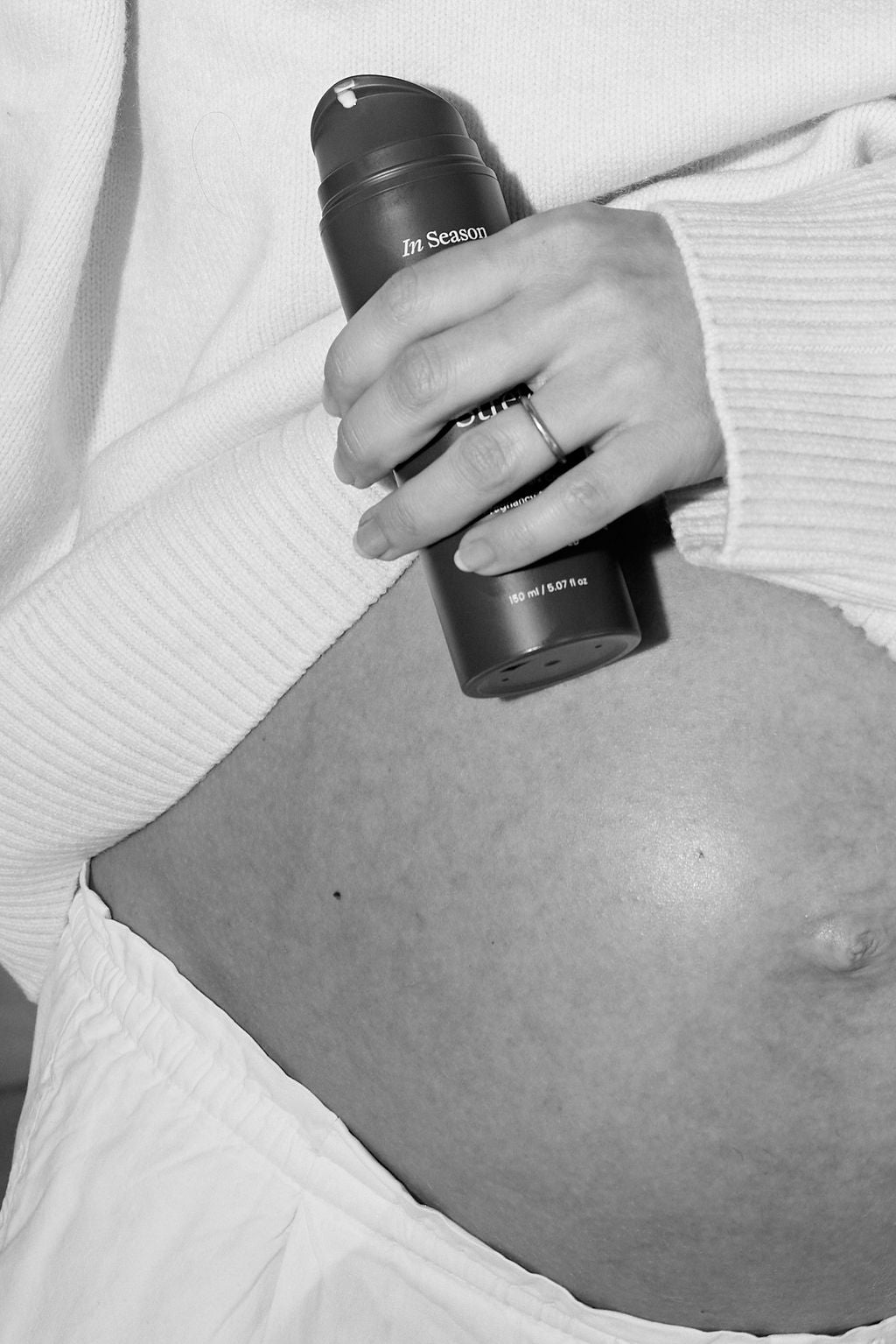 Expecting mother holding in season stretch shield over belly